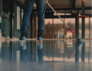Man applying epoxy coating with a non-skid finish to a garage floor.